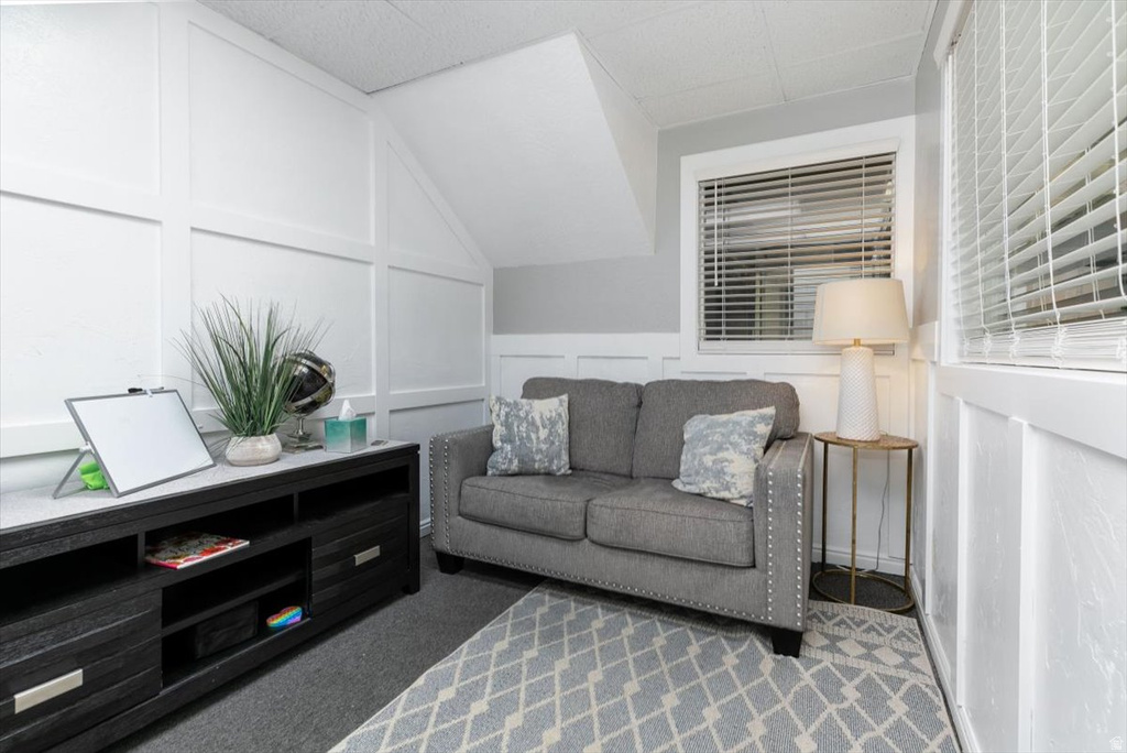 Living area with a decorative wall, vaulted ceiling, and carpet floors