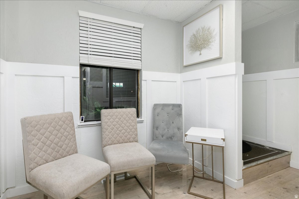 Sitting room with a decorative wall, wood finished floors, and a wainscoted wall