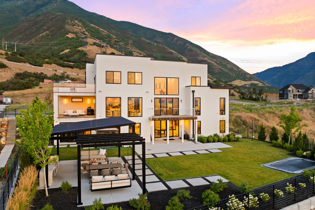 Back of property with a patio area, a mountain view, an outdoor living space, stucco siding, and a pergola
