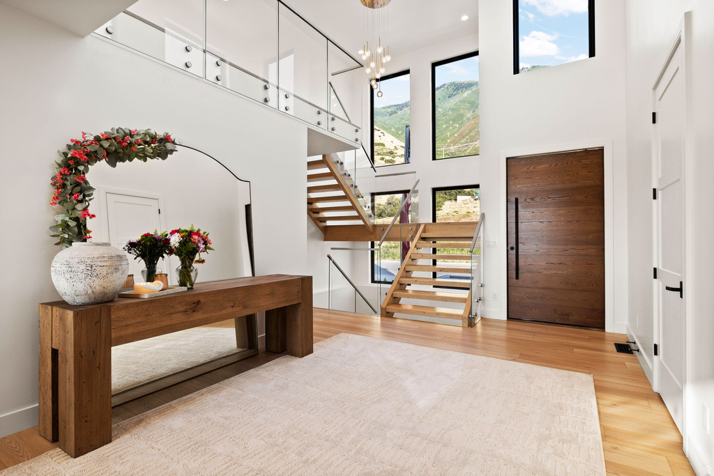 Entrance foyer with light wood-type flooring, suspended lighting, and a high ceiling