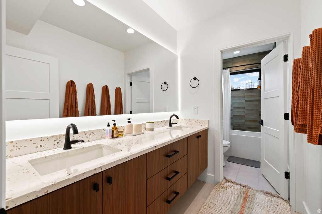 Bathroom with double vanity, shower / tub combo, light tile patterned floors, and recessed lighting