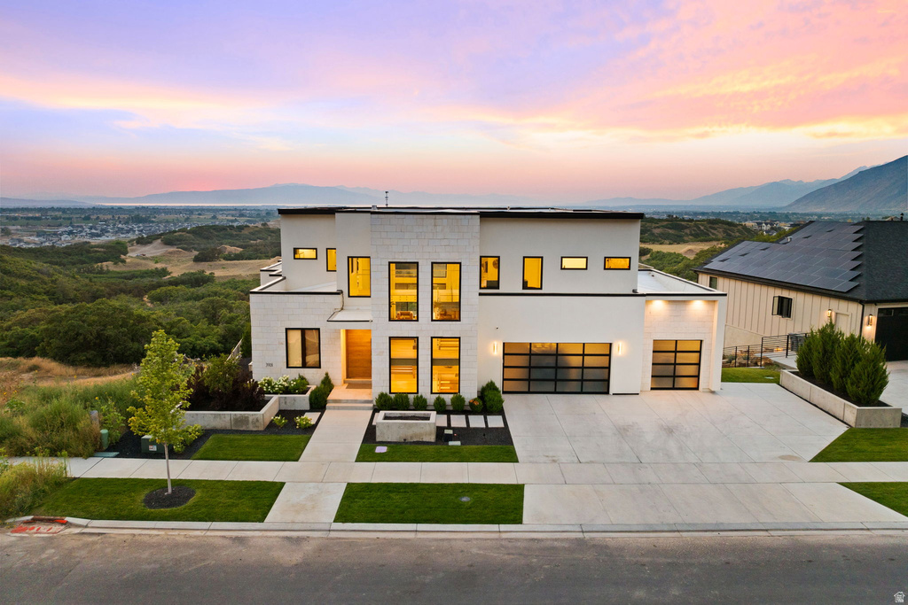 Contemporary home with driveway, a mountain view, stucco siding, and a garage
