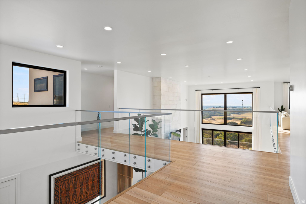 Corridor with healthy amount of natural light, light wood-style floors, and recessed lighting