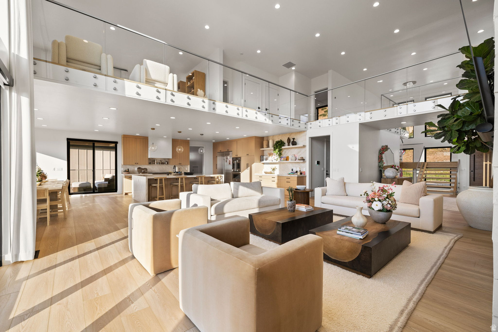 Living room featuring a high ceiling, recessed lighting, and light wood-style floors