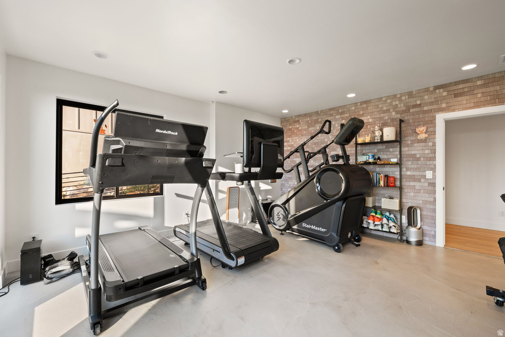 Workout room featuring brick wall, recessed lighting, and finished concrete flooring