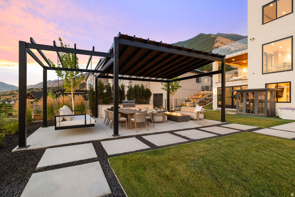 View of patio featuring a pergola, a mountain view, an outdoor fire pit, and an outdoor kitchen with living area