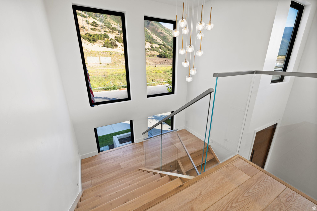 Stairway with hanging lights, plenty of natural light, wood finished floors, and a mountain view