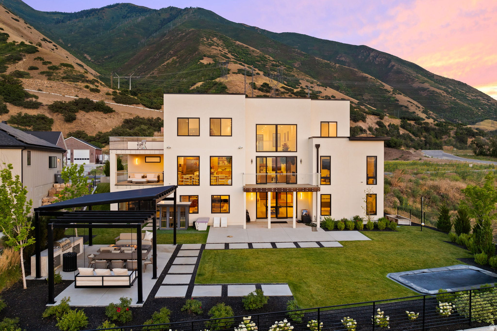 Back of property at dusk with a patio area, an outdoor living space, a mountain view, and stucco siding