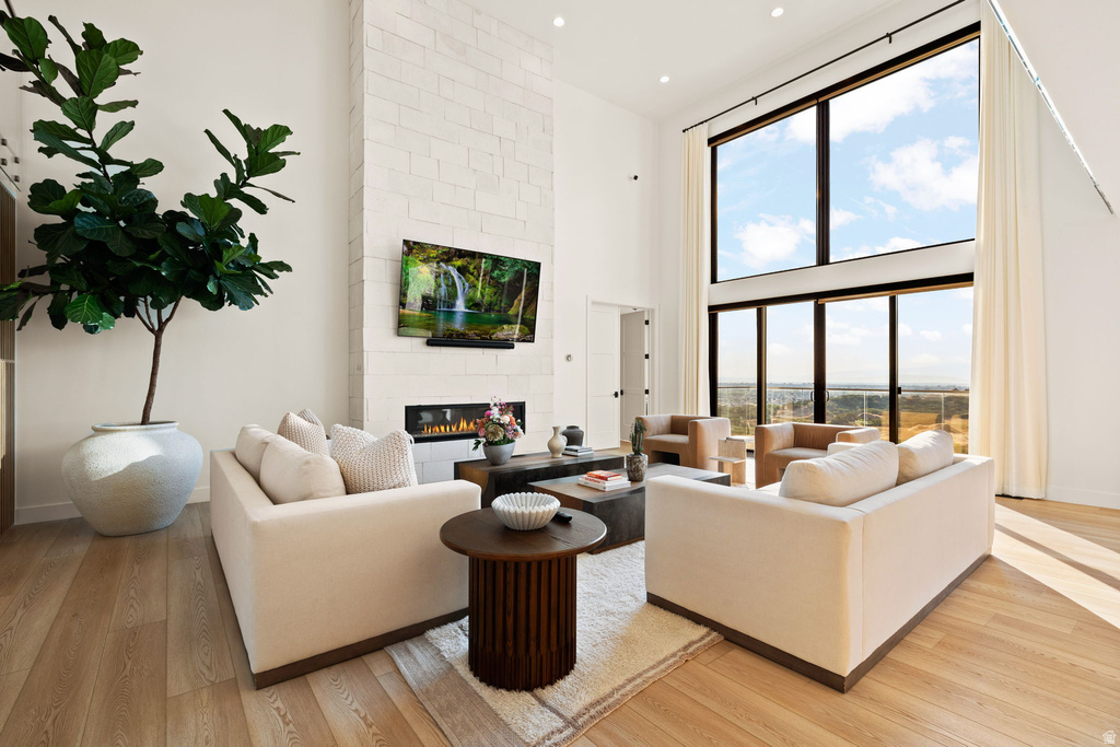Living area with light wood-type flooring, a high ceiling, a fireplace, and recessed lighting
