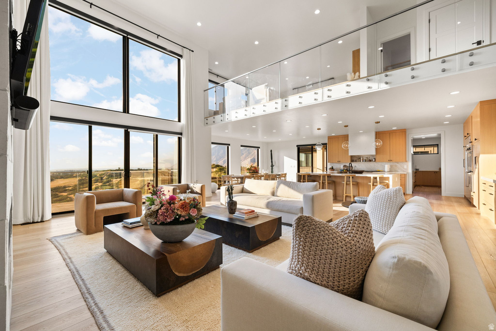 Living area with light wood finished floors, a high ceiling, and recessed lighting