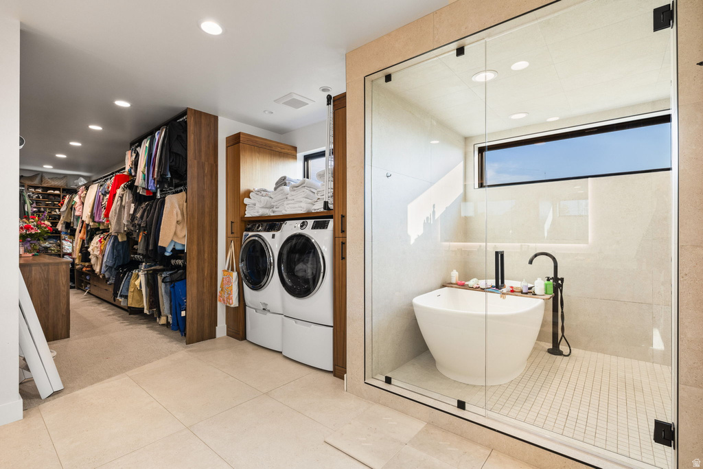 Full bathroom with a walk in closet, separate washer and dryer, recessed lighting, light tile patterned flooring, and a freestanding bath