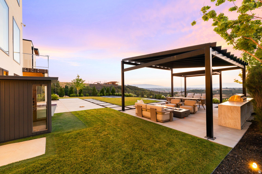 Yard at dusk with an outdoor living space with a fire pit, a yard, and a patio area