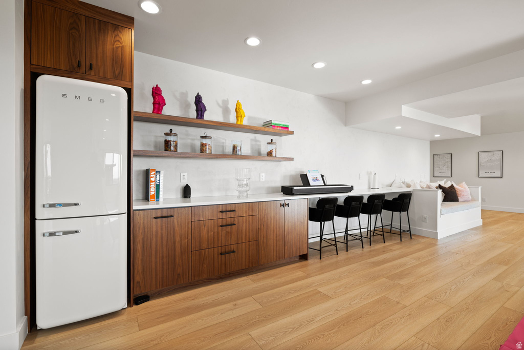 Bar with freestanding refrigerator, light wood finished floors, recessed lighting, open shelves, and wood finish cabinetry