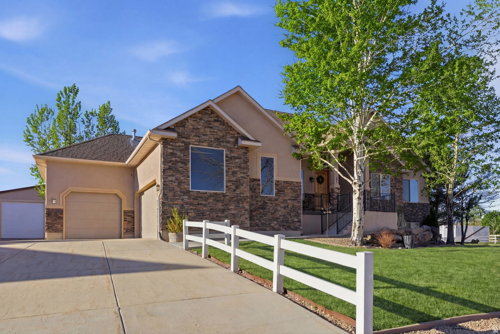 View of front of property with stone siding, stucco siding, concrete driveway, and an attached garage