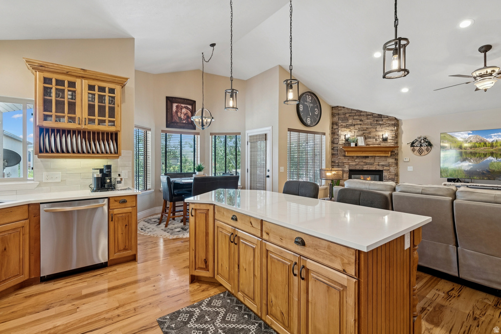 Kitchen featuring dishwasher, glass fronted cabinets, a fireplace, a kitchen island, and light wood finished floors