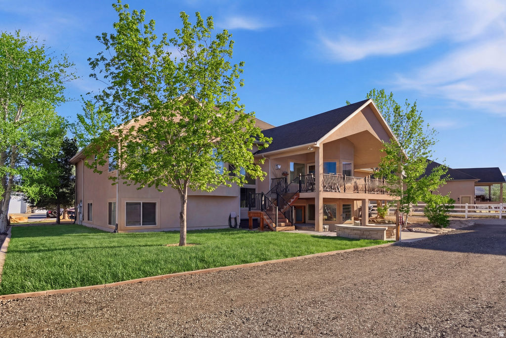 Back of house with a patio area, a wooden deck, a yard, and stucco siding