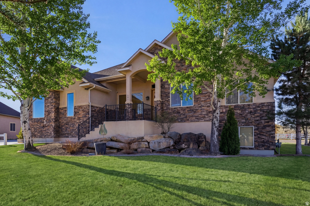 View of front of house featuring stone siding, stucco siding, and a front lawn