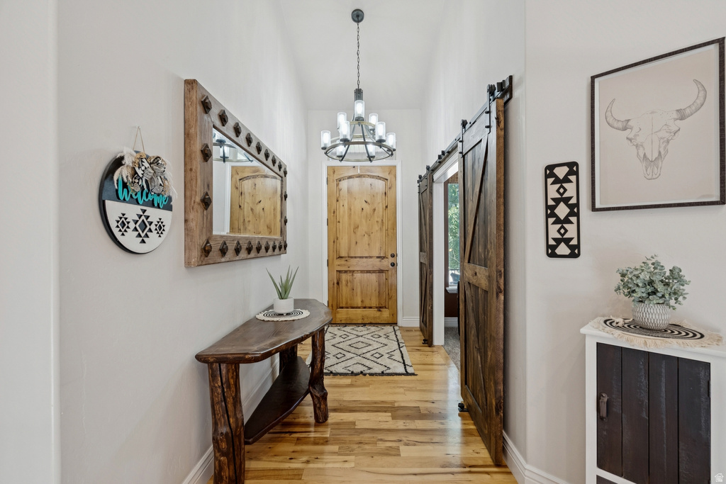 Entryway with a barn door, suspended lighting, and wood finished floors