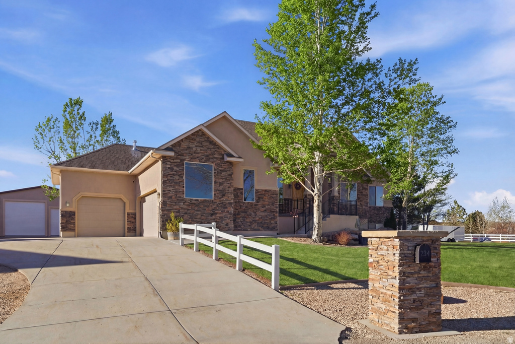 Ranch-style home with stucco siding, stone siding, driveway, and a garage