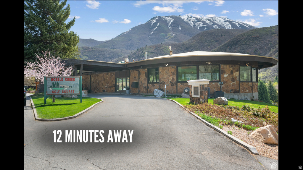 View of front facade featuring a mountain view, stone siding, and a front lawn