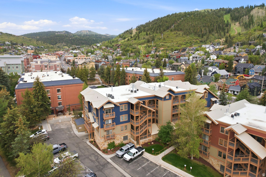 Multi-story building featuring natural stone and wood siding, individual balconies, and a paved parking area