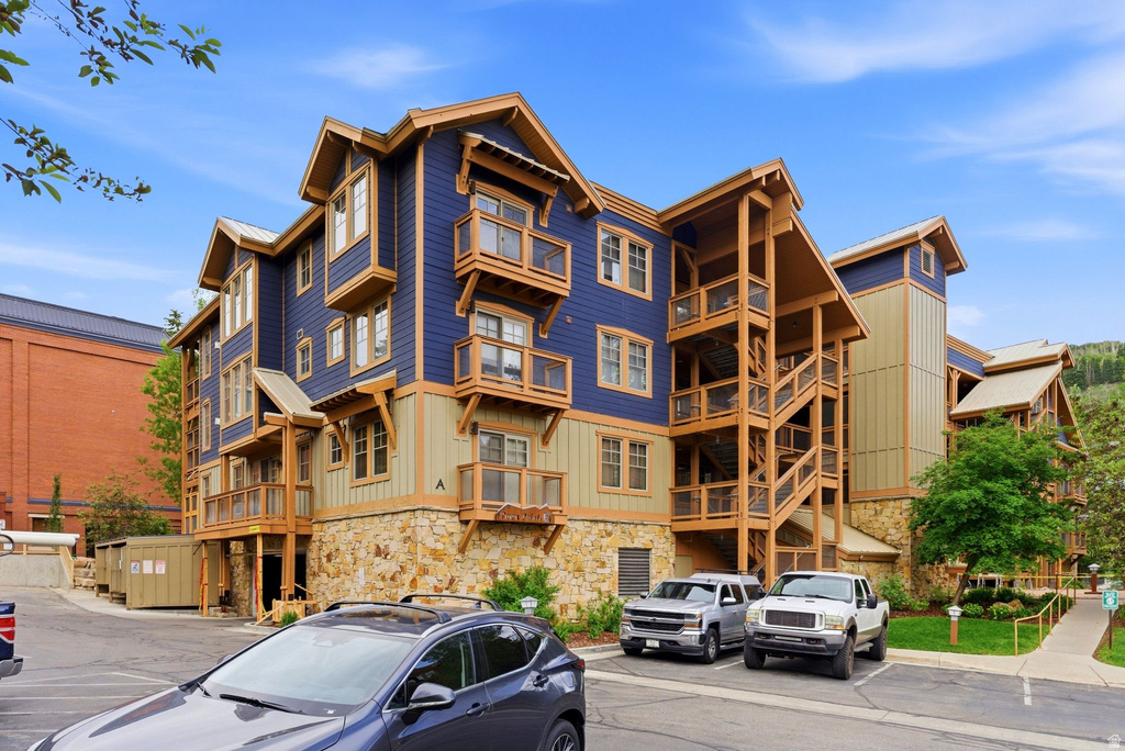 Multi-story condominium building featuring blue and tan siding, stone facade, and extensive wood-finish balcony and stair structures