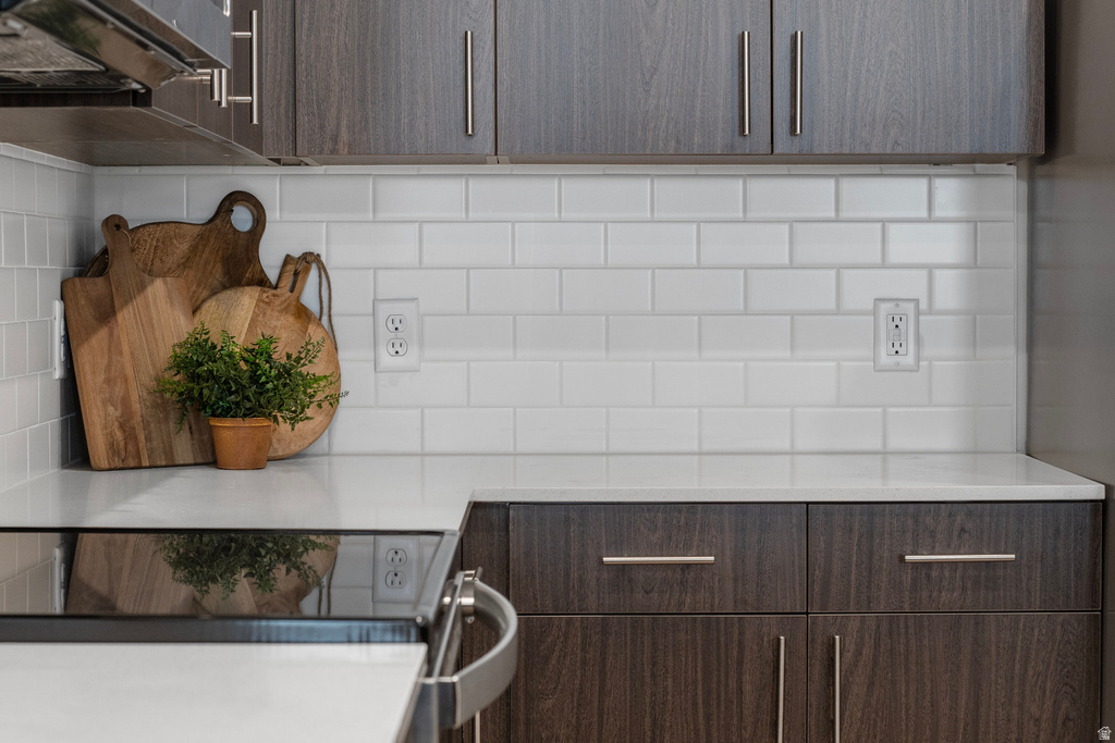 Kitchen view of modern cabinets, dark wood finish cabinetry, black / electric stove, and light stone countertops