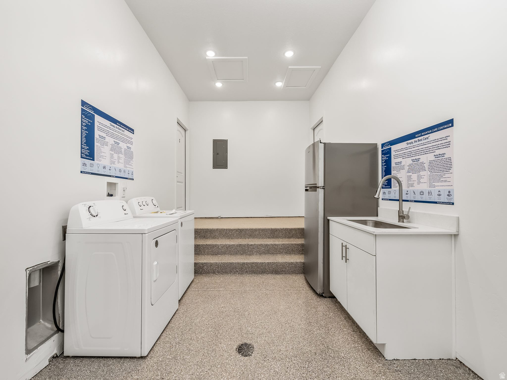 Laundry area featuring dark speckled floor, washing machine and clothes dryer, and electric panel