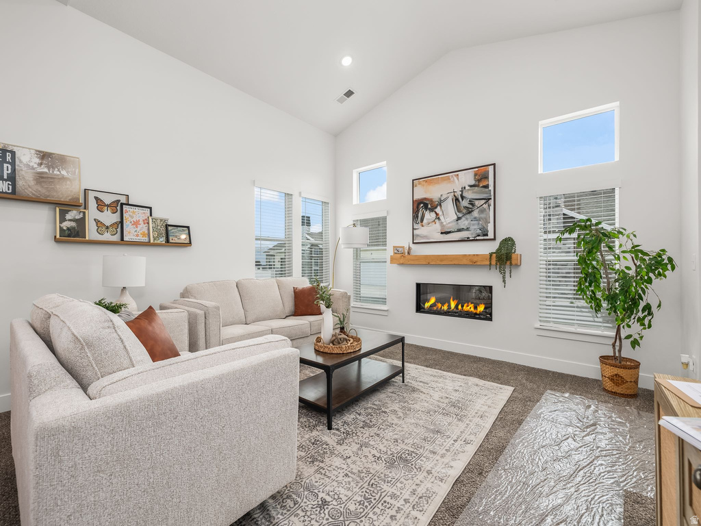 Living area featuring a glass covered fireplace, carpet, recessed lighting, and lofted ceiling