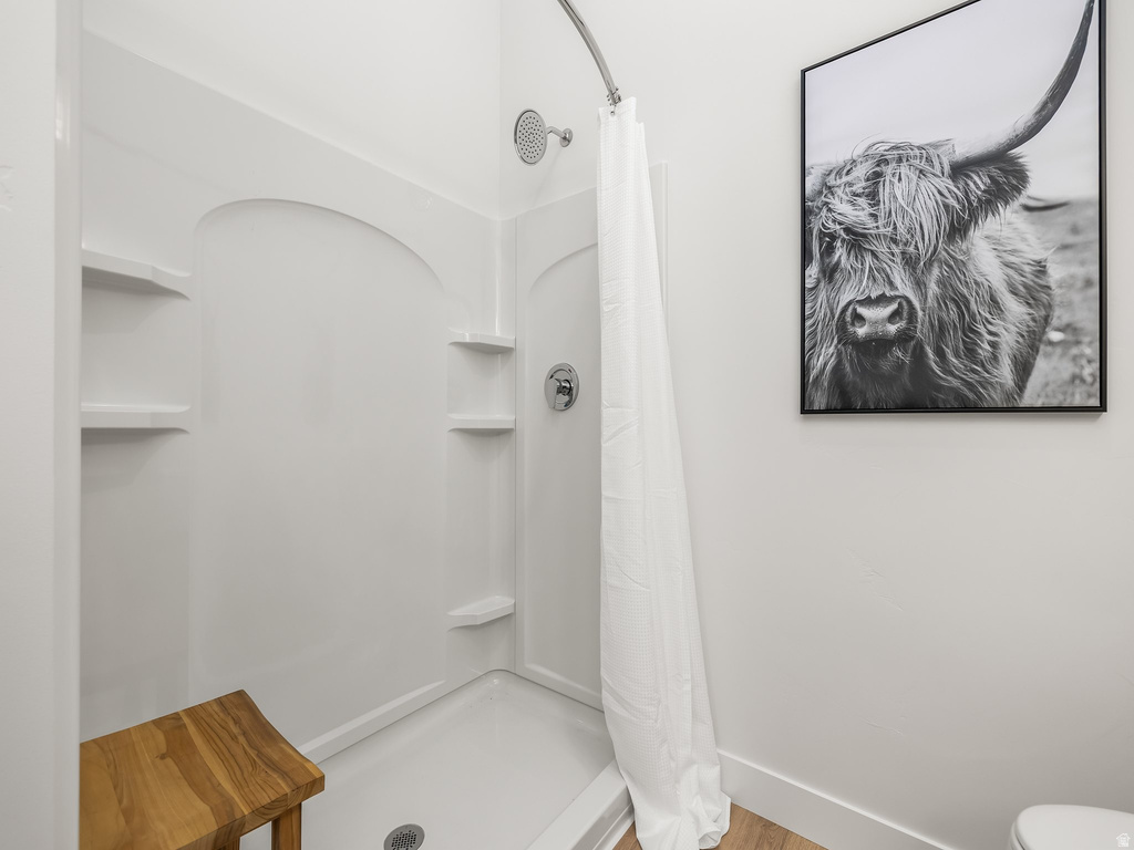 Full bath with a stall shower and wood finished floors