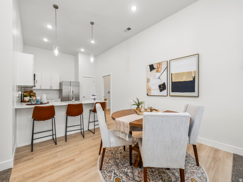 Dining area with light wood-style floors, recessed lighting, and a high ceiling