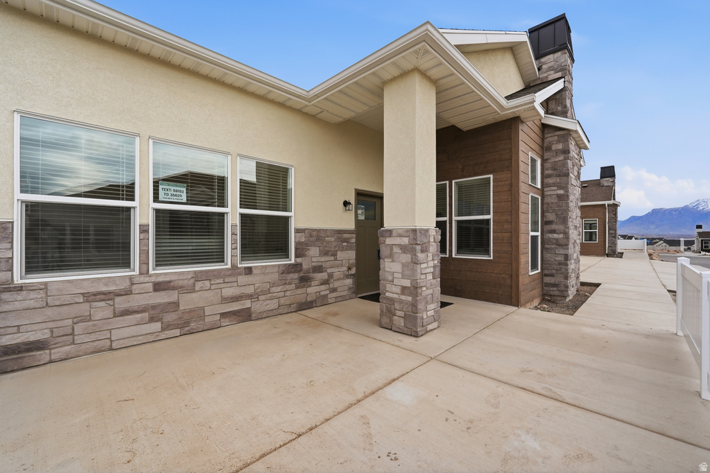 View of exterior entry featuring stucco siding, stone siding, a patio, and a mountain view