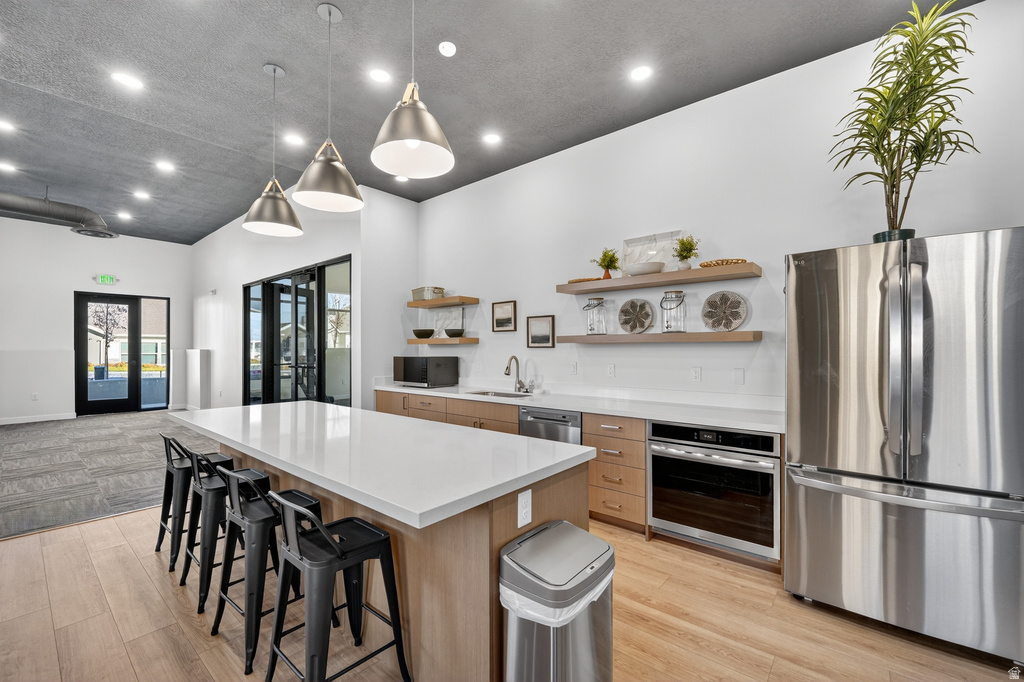 Kitchen featuring light wood-style floors, stainless steel appliances, a kitchen island, open shelves, and open floor plan