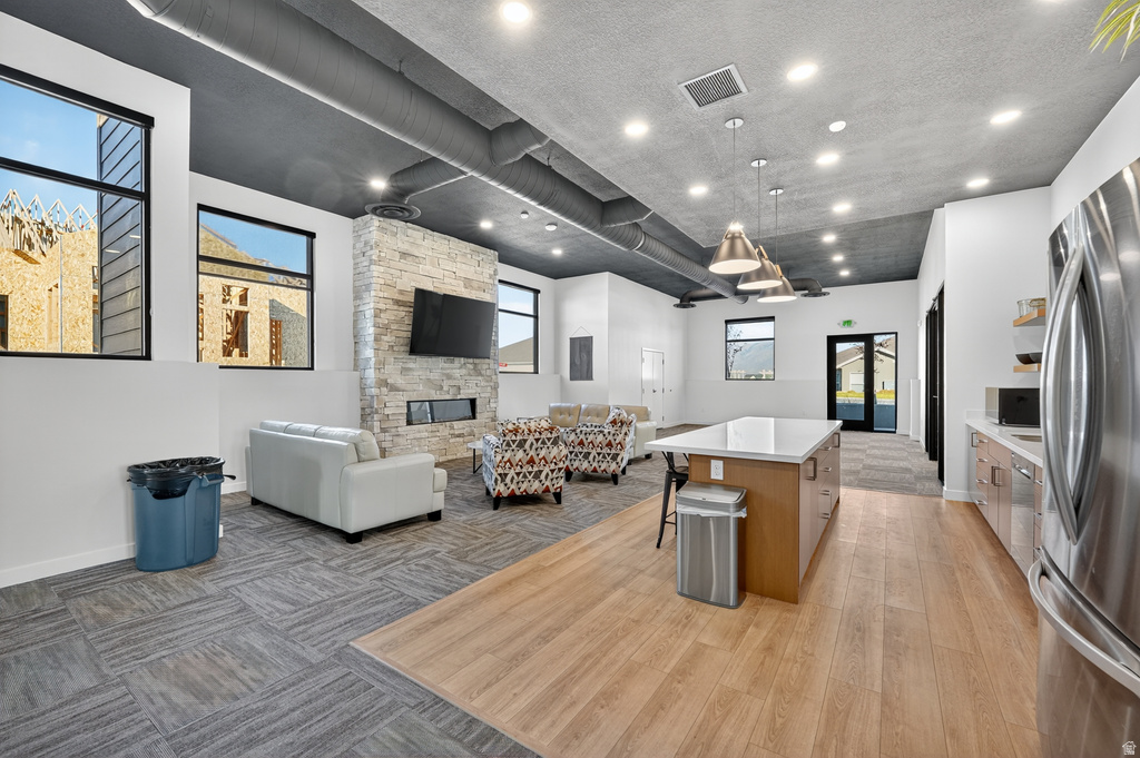 Kitchen with a kitchen island, open floor plan, open shelves, freestanding refrigerator, and a breakfast bar area