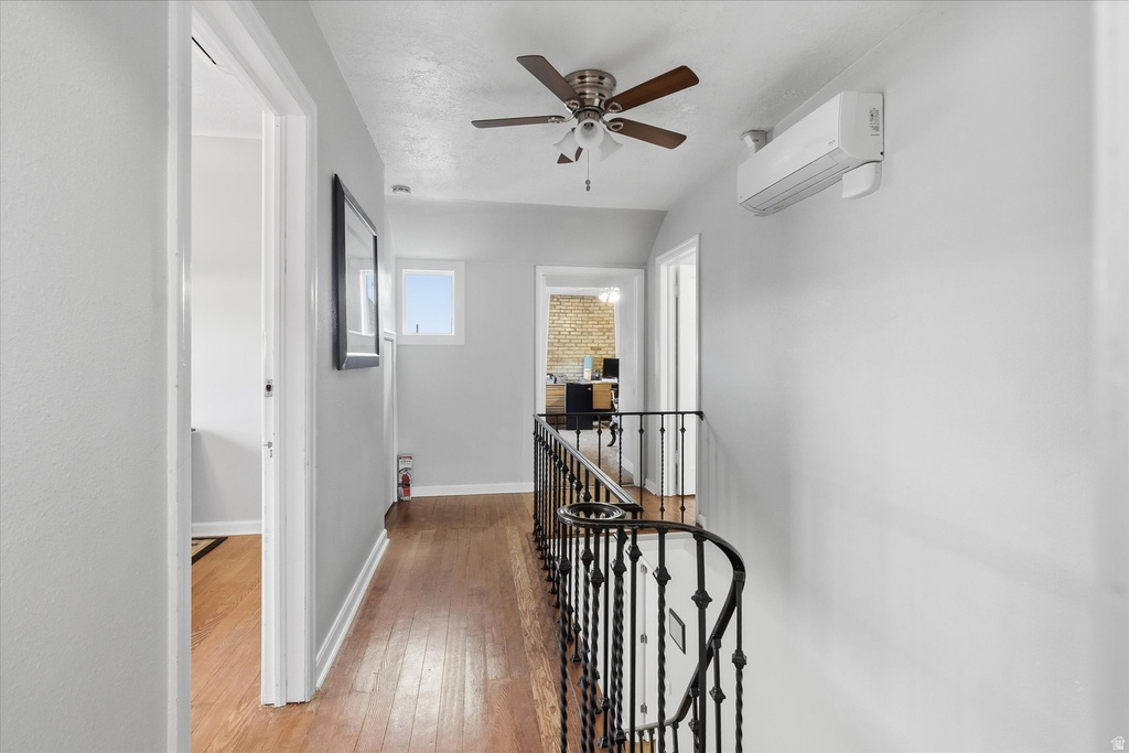 Corridor featuring an upstairs landing, light wood-type flooring, and a wall mounted mini split