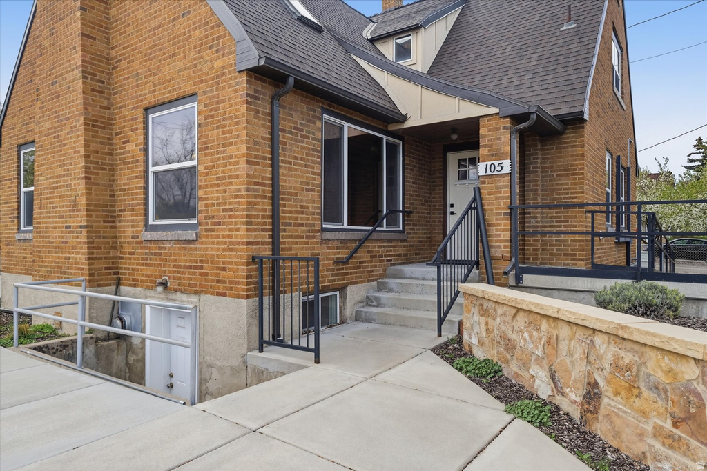 View of front of home with a shingled roof and brick siding