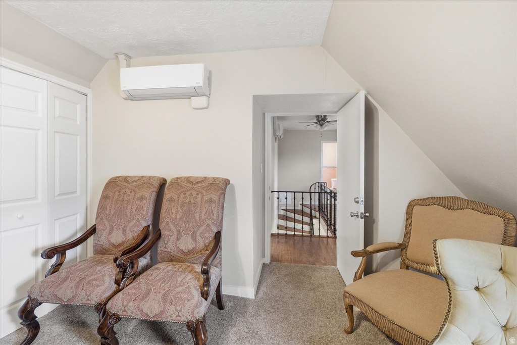 Living area with carpet, an upstairs landing, and a ceiling fan