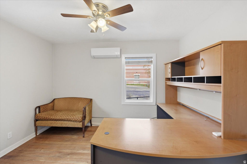 Home office featuring light wood-style flooring, built in desk, and a ceiling fan