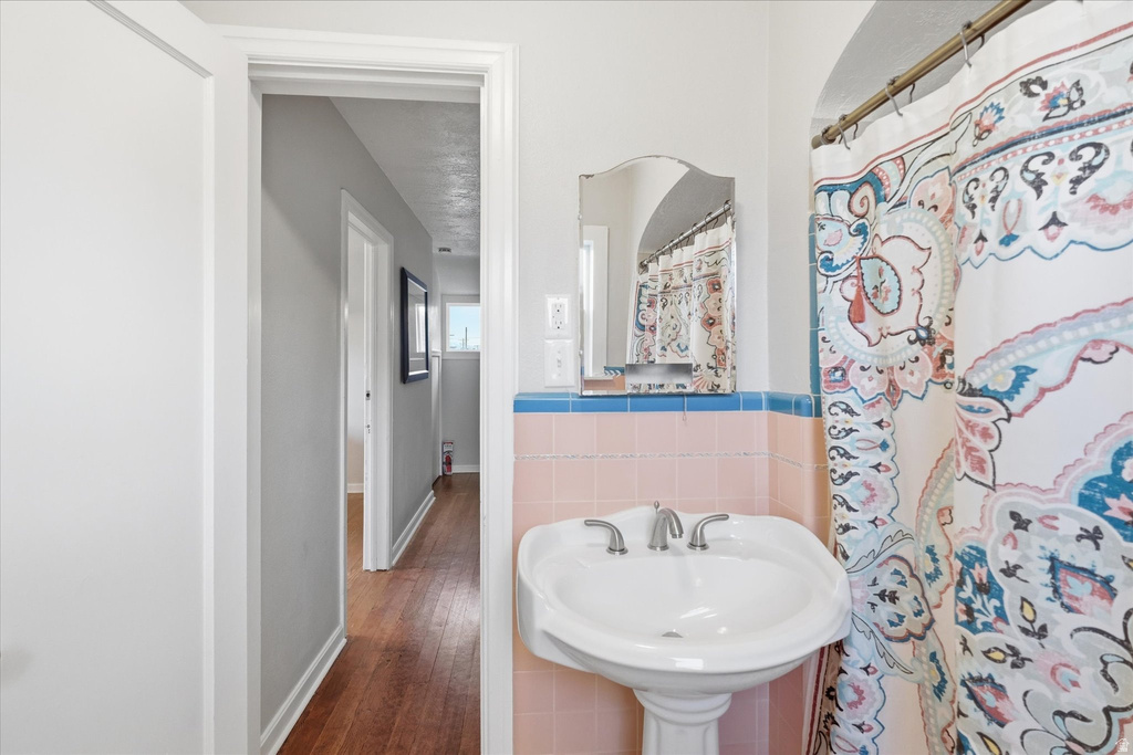 Bathroom with tile walls, curtained shower, and dark wood-style floors