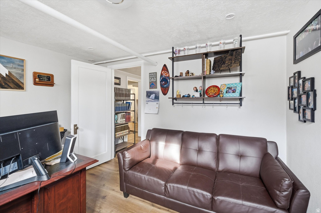 Living room featuring a textured ceiling, wood finished floors, and a desk