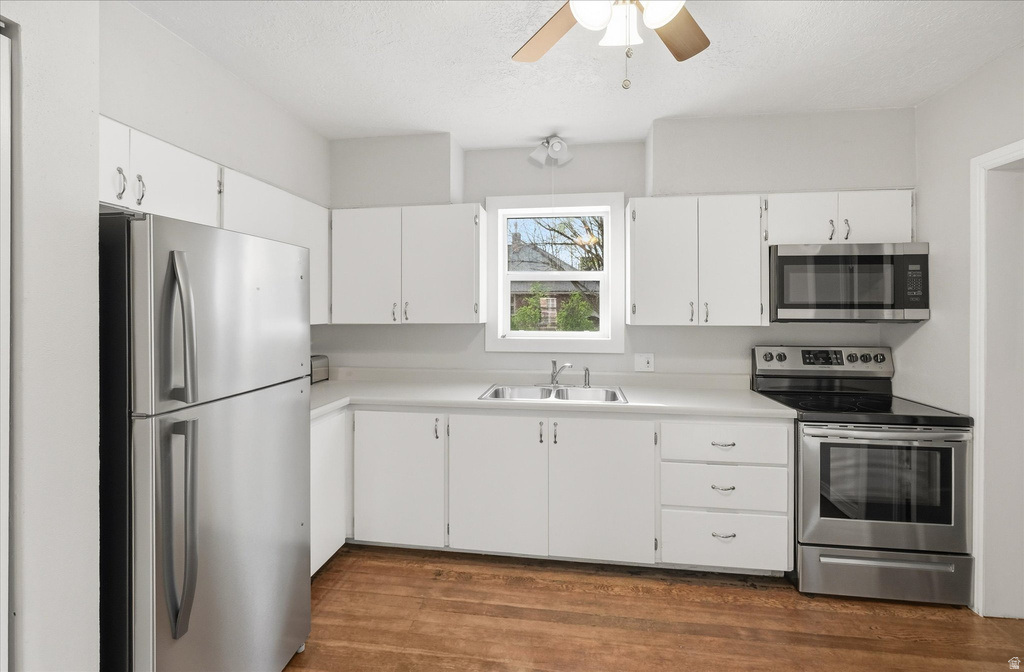 Kitchen featuring stainless steel appliances, white cabinets, light countertops, and ceiling fan