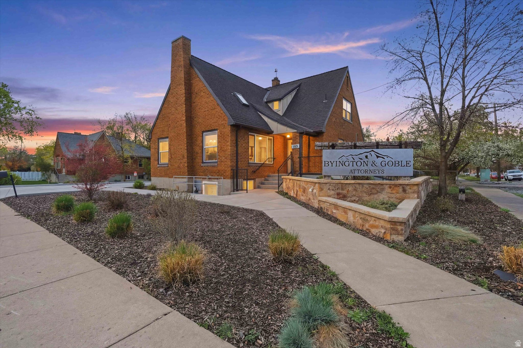 View of front of home with a chimney, brick siding, and a shingled roof