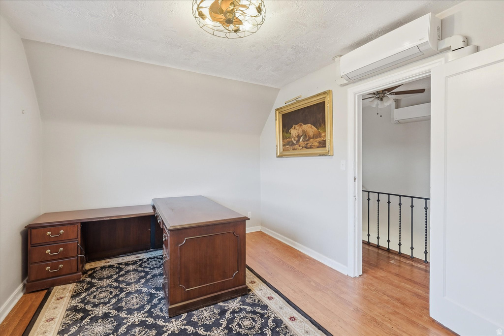 Office space with a wall mounted mini split, light wood-style flooring, and ceiling fan