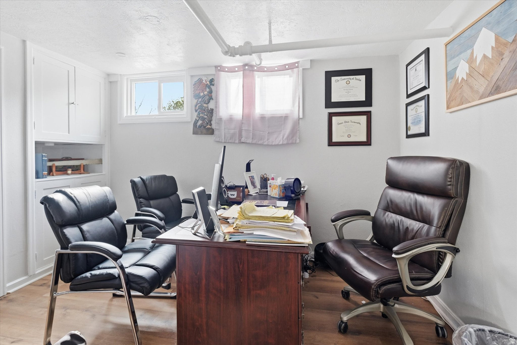 Office with a textured ceiling and wood finished floors