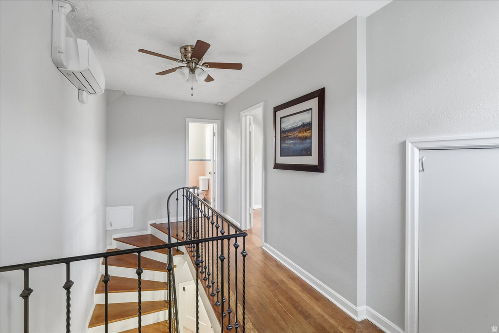 Hallway with an upstairs landing, light wood-style floors, and a mini split for heating / cooling