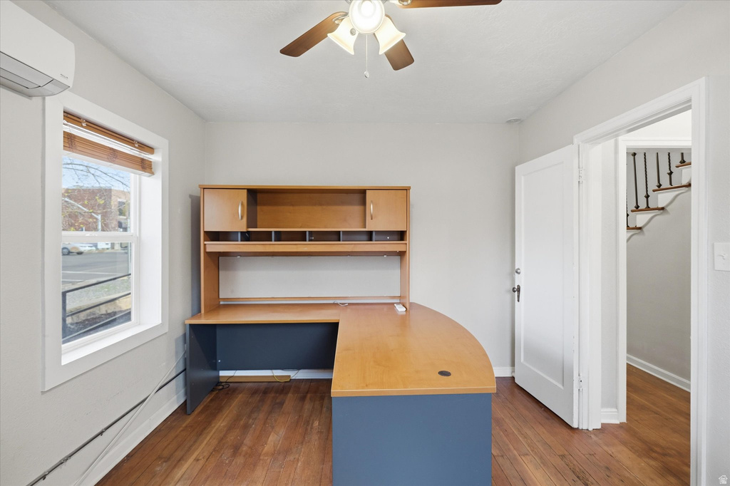 Unfurnished office with built in study area, ceiling fan, and dark wood finished floors