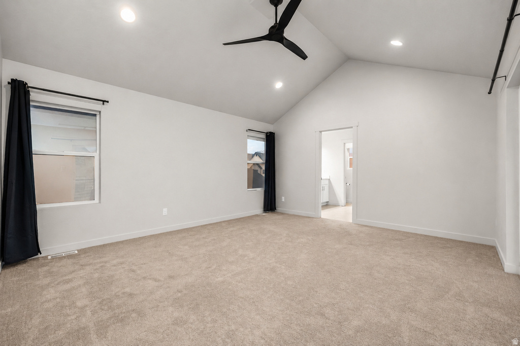 Vaulted ceiling room featuring light neutral carpeting, recessed lighting, and a contemporary black ceiling fan