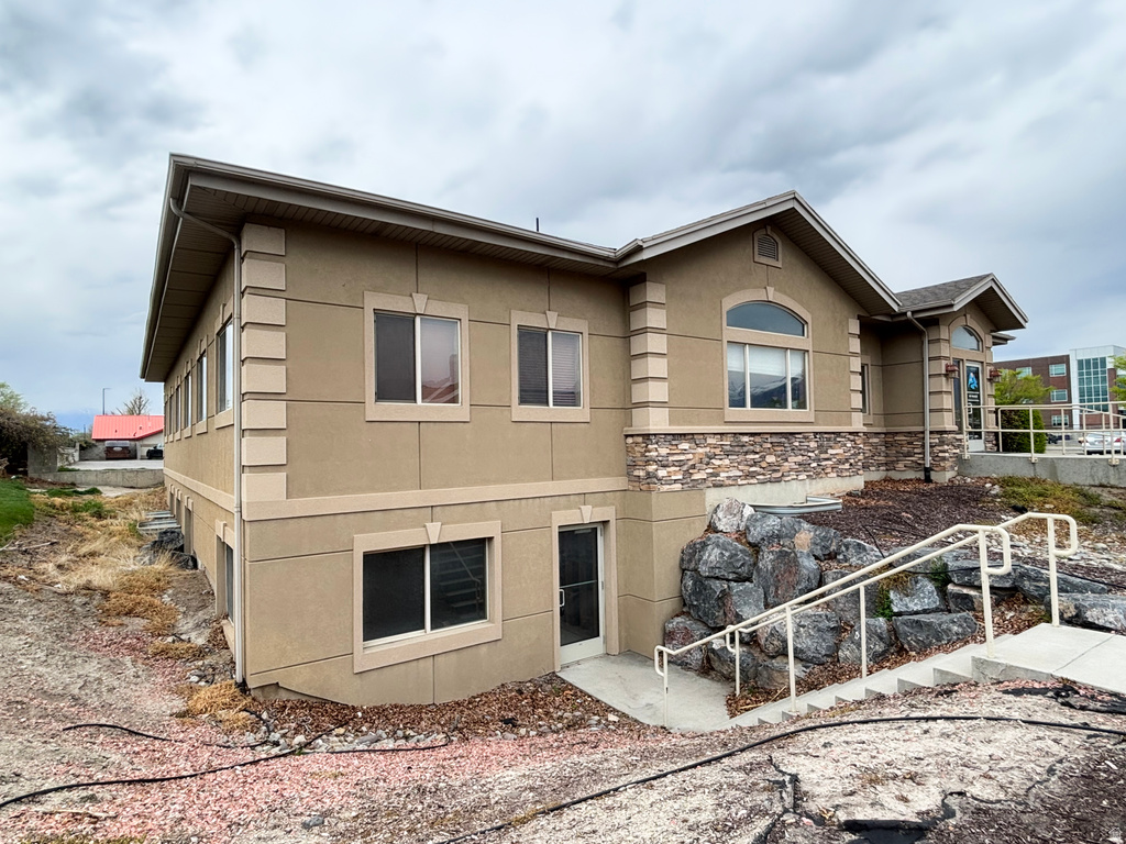 Rear view of property with stucco siding and stone siding