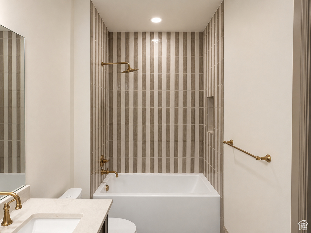 Bathtub with brass fixtures, vertically-striped tiled shower surround, recessed shower niche, and built-in vanity with single sink