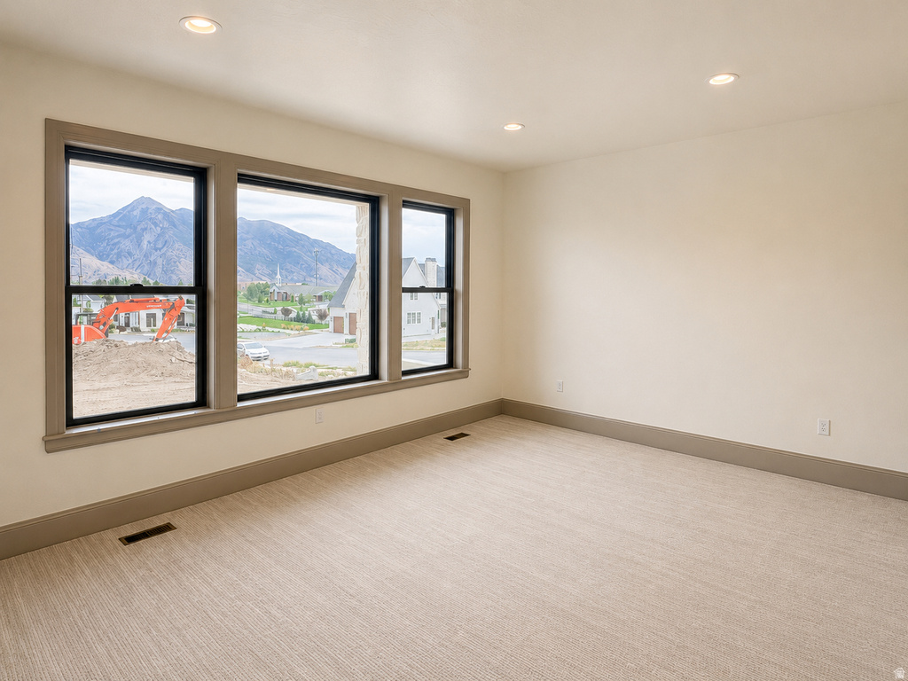 Recessed lighting, light-toned walls, and neutral carpeting